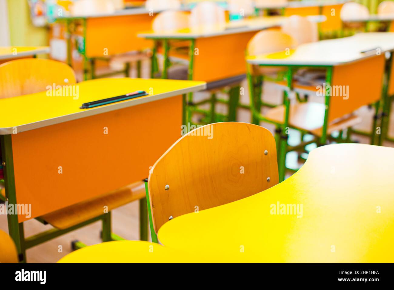 Sedie e scrivanie in un'aula deserta in una scuola Foto Stock
