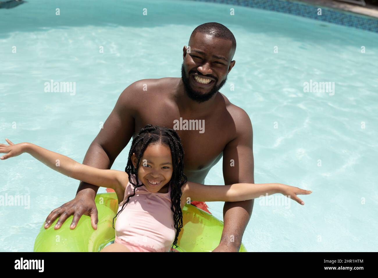 Ritratto di allegro padre e figlia afro-americana godendo giorno di sole in piscina nel cortile Foto Stock