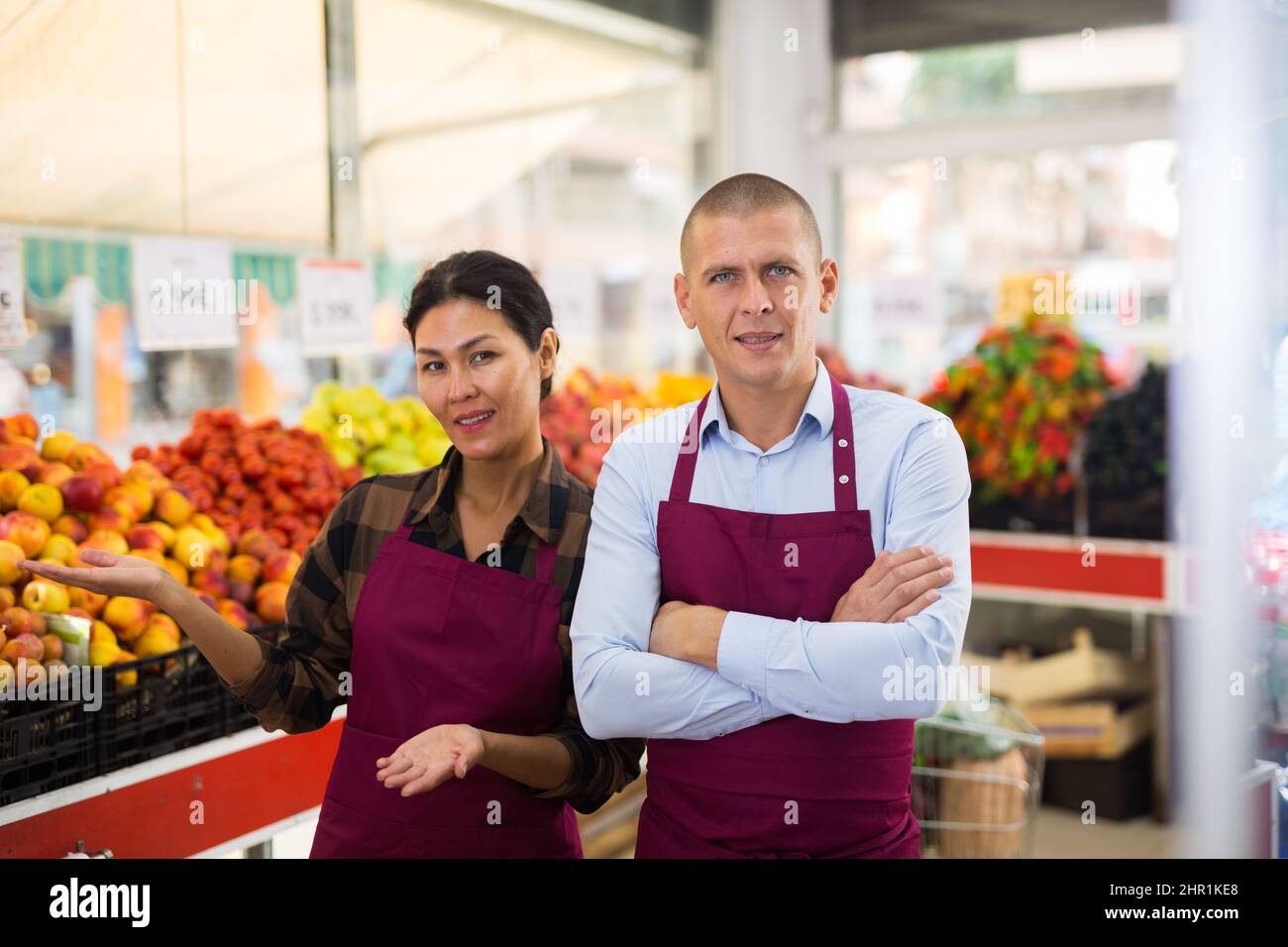 Venditori sorridenti che raccomandano prodotti biologici al mercato degli agricoltori Foto Stock