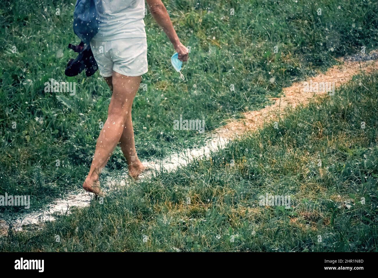 i piedi delle donne camminano a piedi nudi su un percorso bagnato con le pozzanghere Foto Stock