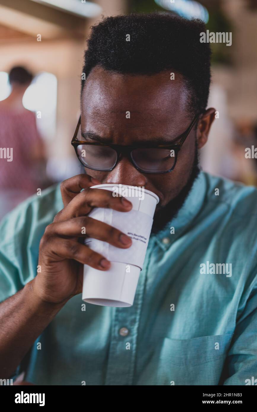 uomo nero bere caffè con camicia blu Foto Stock