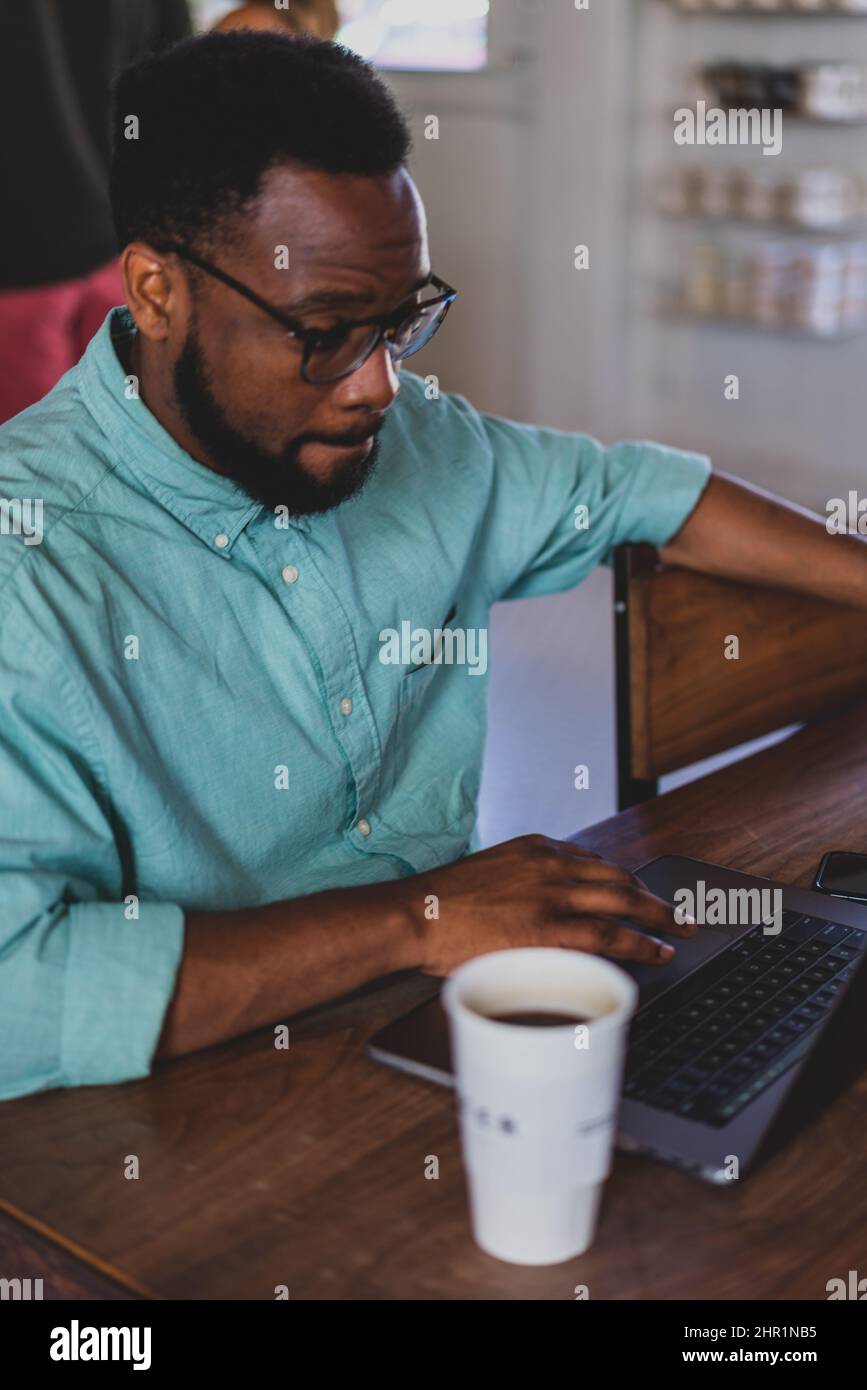 giovane professionista che usa il laptop in caffetteria Foto Stock