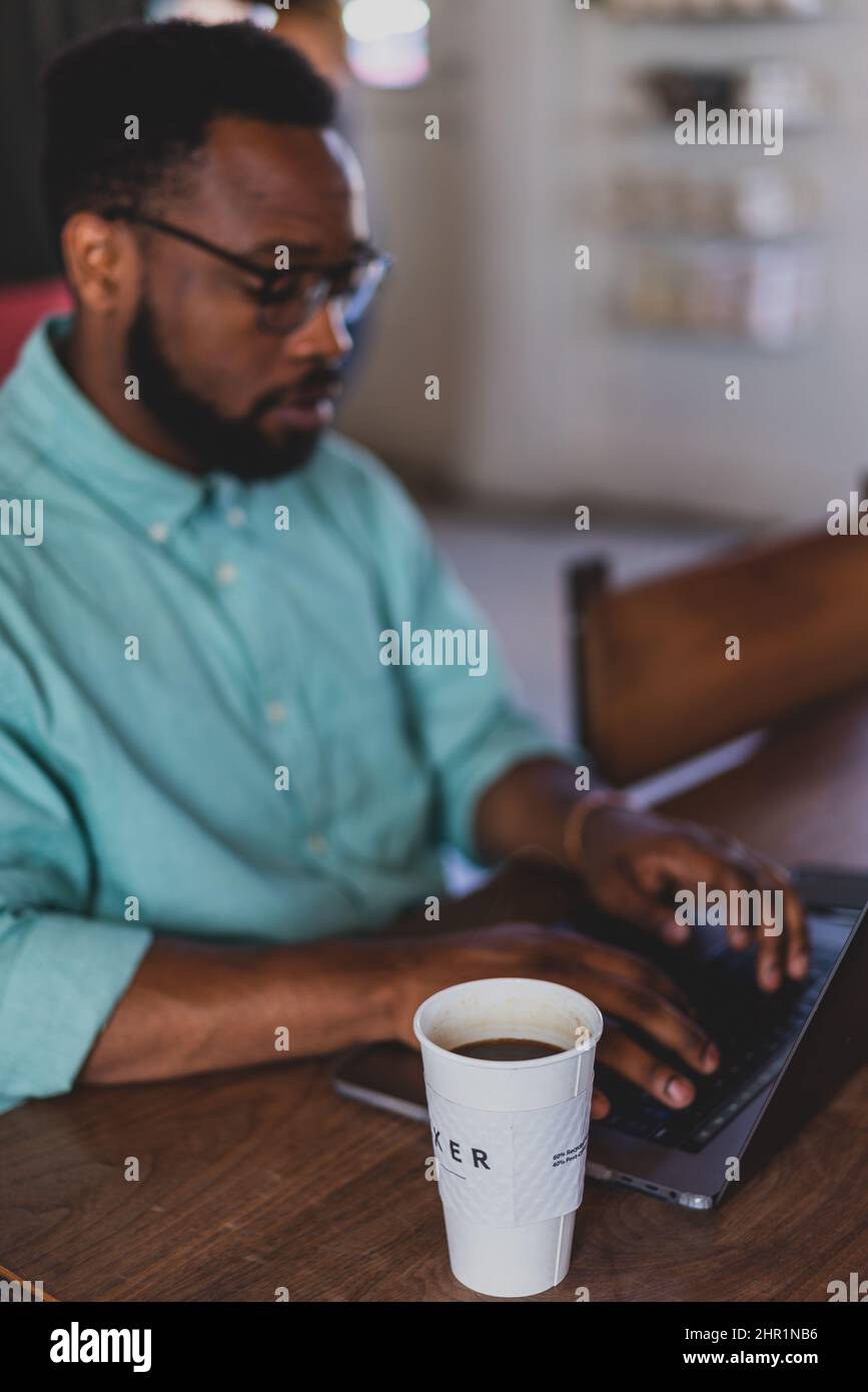 giovane uomo nero che digita sul laptop in caffetteria Foto Stock