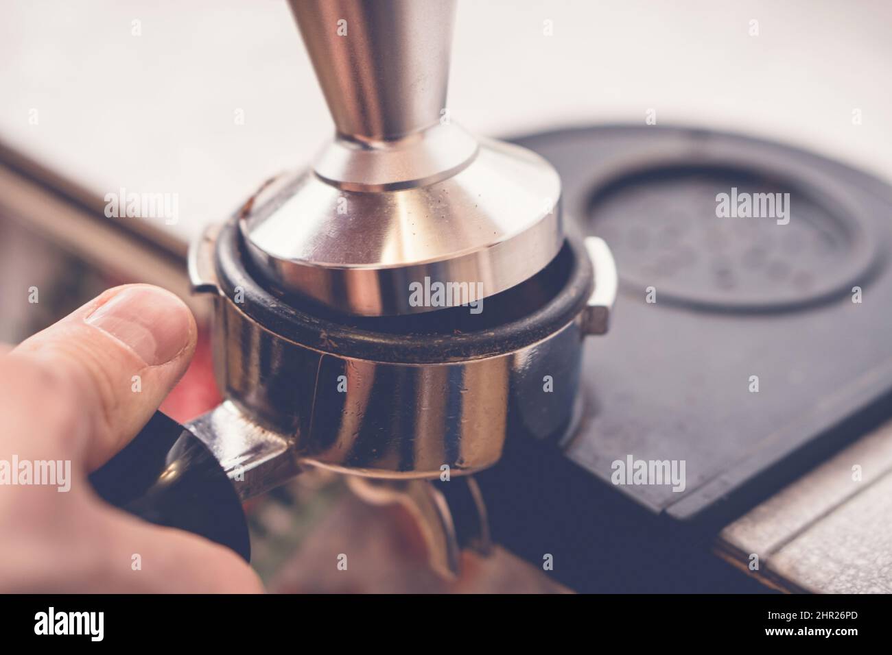 Barista manomissione caffè in portafiltro con manomissione. Primo piano del processo di preparazione del caffè fresco Foto Stock