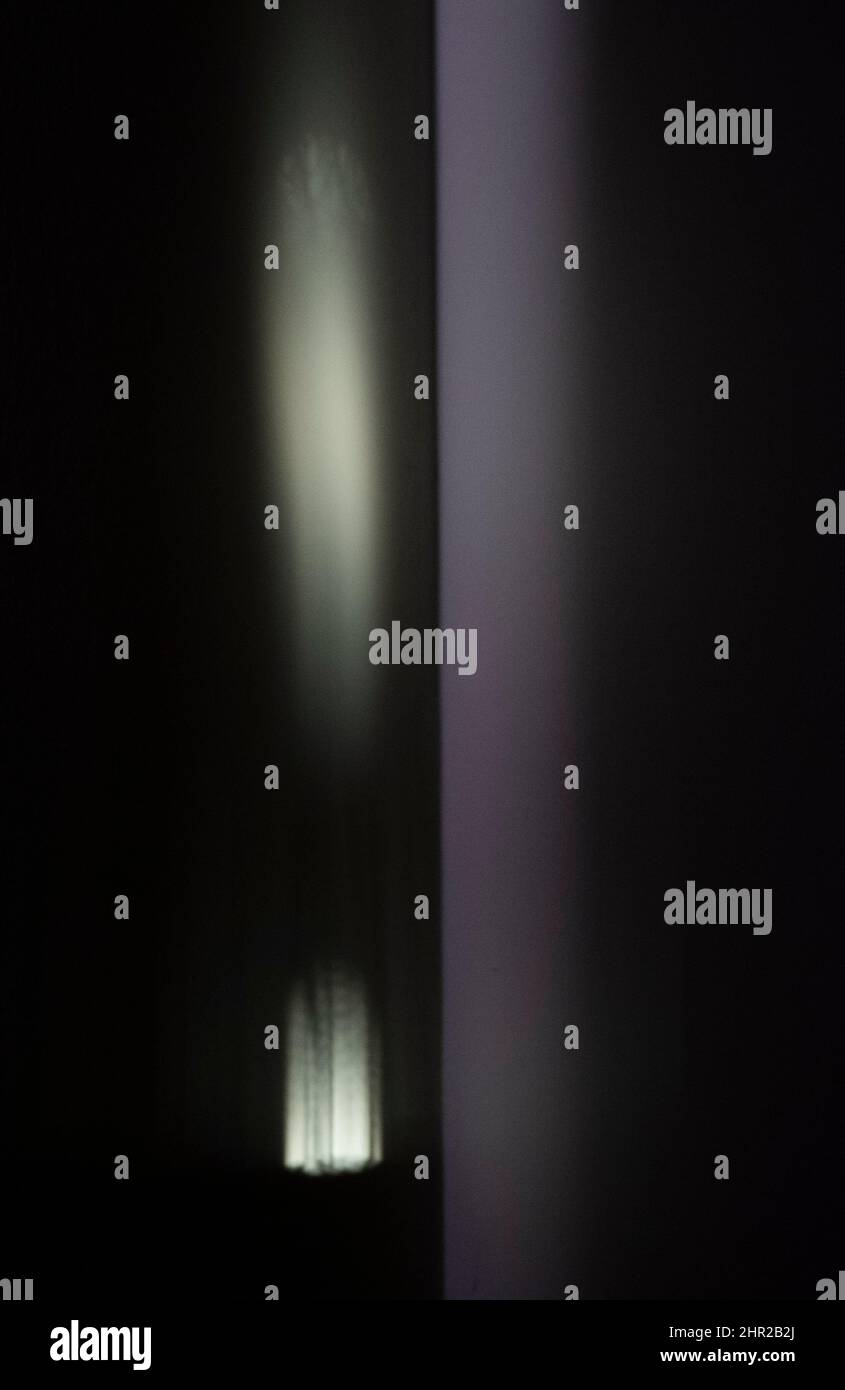 La prima luce del giorno si riflette sulla parete di una camera da letto e in uno specchio creando curiose forme astratte luminose. Foto Stock