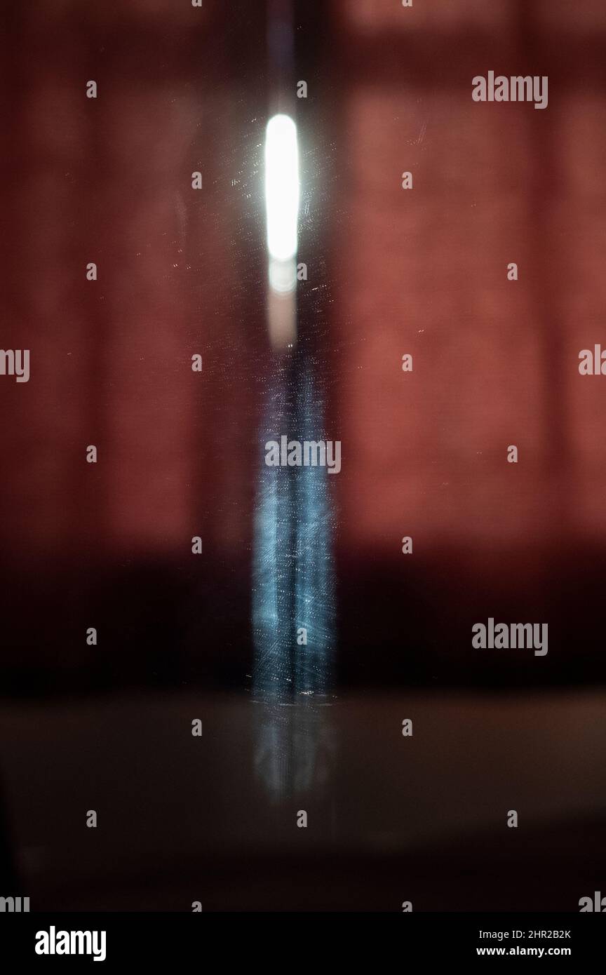 La prima luce del giorno si riflette sulla parete di una camera da letto e in uno specchio creando curiose forme astratte luminose. Foto Stock