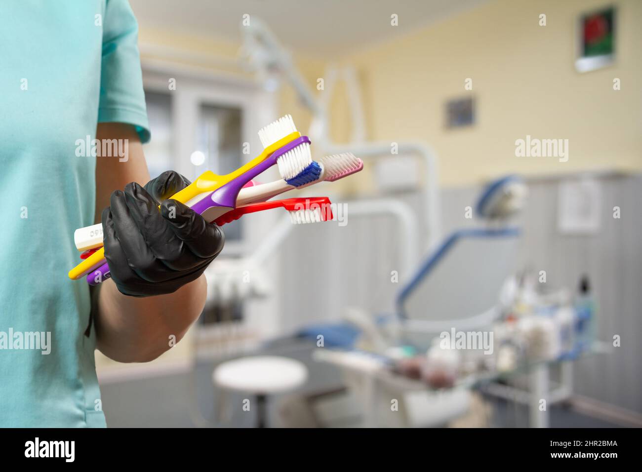Mano del dentista in guanto protettivo con spazzolini da denti. Foto Stock