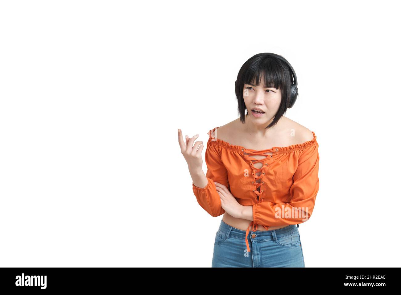 Giovane donna asiatica con cuffie che puntano a qualcosa di sorpreso, isolato. Foto Stock