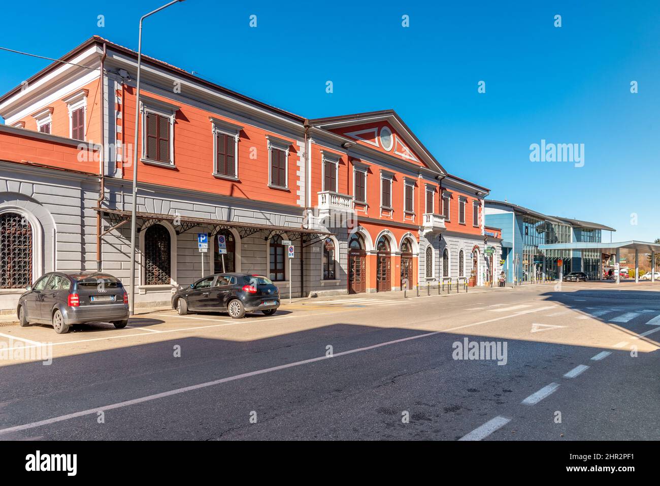 Fossano, Italia - 22 febbraio 2022: Stazione ferroviaria di Fossano, antico edificio neoclassico in primo piano e moderno edificio blu nel retro Foto Stock