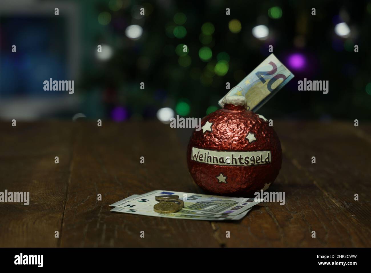 Un primo piano di soldi in una banca di maialino nella forma di un ornamento dell'albero di Natale Foto Stock
