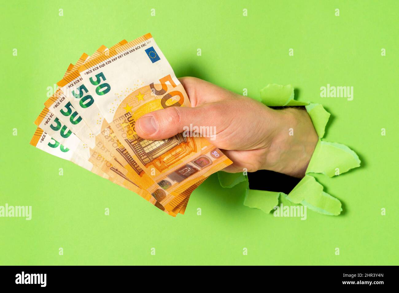 Uomo d'affari che si spezzi attraverso il Libro verde con soldi a portata di mano, primo piano Foto Stock