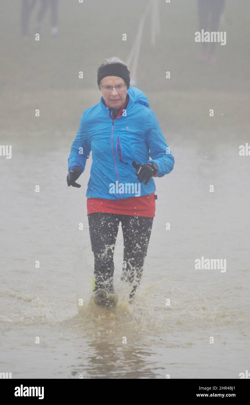 le donne pensionati che corrono club cross country corsa attraverso il rischio d'acqua Foto Stock