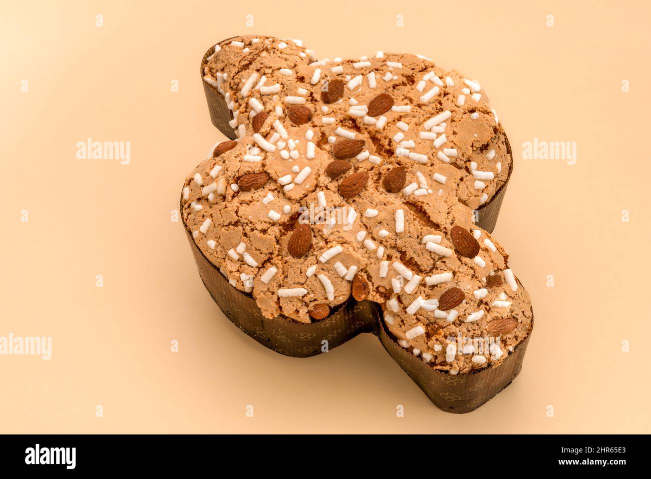 Colomba Pasquale su sfondo marrone chiaro, dolce tipico italiano di pasqua con glassa di zucchero e mandorle. Pasqua dove in inglese. Foto Stock