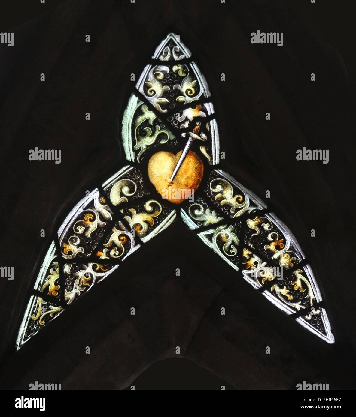 Vetrata di Percy Bacon & Brothers,; luce traforata; spada che trafigge un cuore, design; Ernest Geldart, Chiesa di Santa Maria, Coddenham, Suffolk Foto Stock