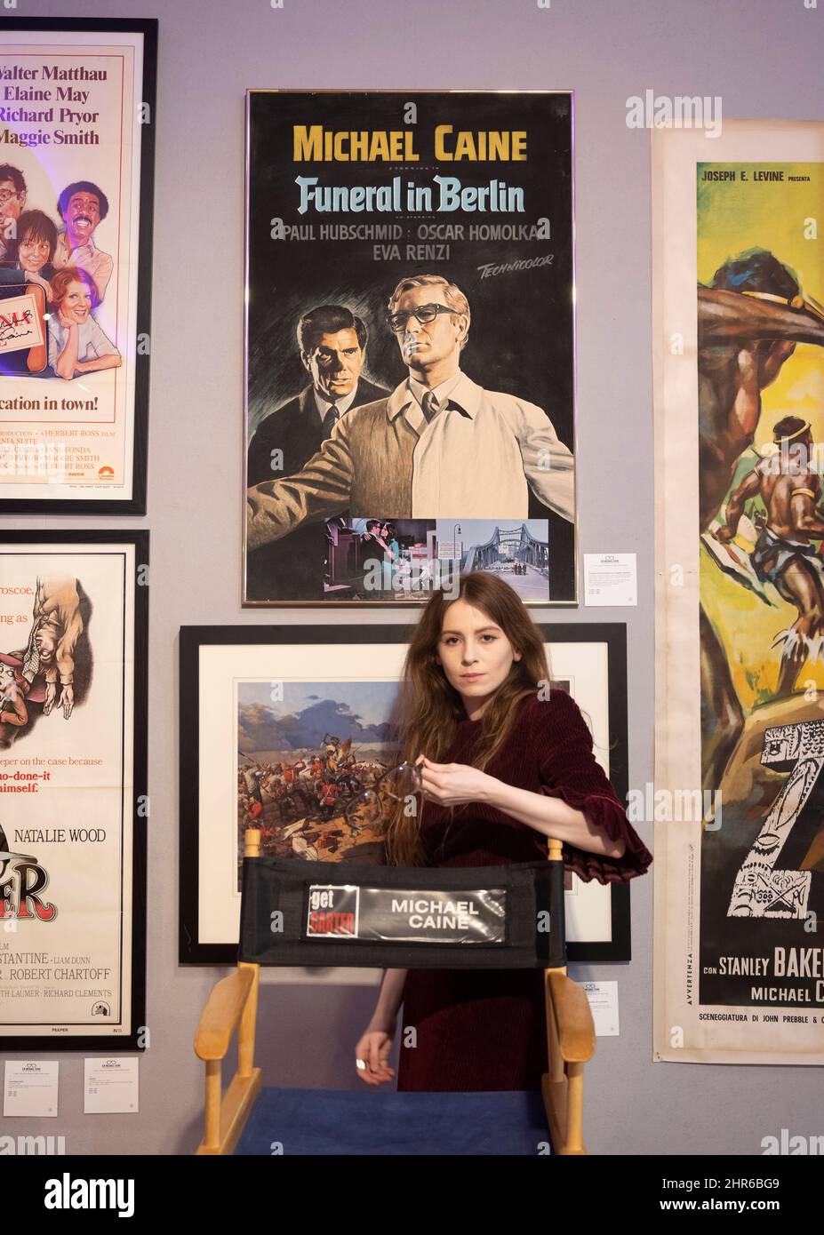 Bonhams, Londra, Regno Unito. 25 febbraio 2022. Sir Michael Caine: La Collezione personale in anteprima prima della vendita il 2 marzo 2022. Lui e sua moglie, Lady Caine, stanno ridimensionando e hanno messo alcuni dei loro beni preziosi in asta. Immagine: Presidente Directors, Get carter davanti al poster del film, funerale a Berlino, membri dello staff Bonhams tiene uno degli attori paia di occhiali, anche in vendita. Credit: Malcolm Park/Alamy Live News Foto Stock