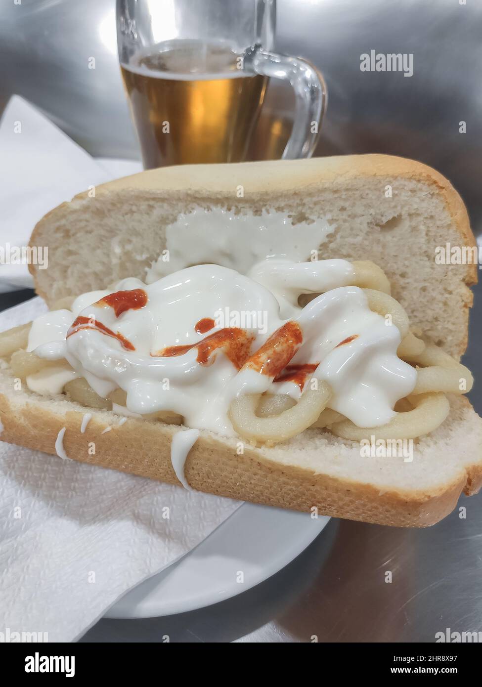 Sandwich al calamari con birra in background. Tipico cibo spagnolo, bocadillo de calamares di Madrid. Foto Stock