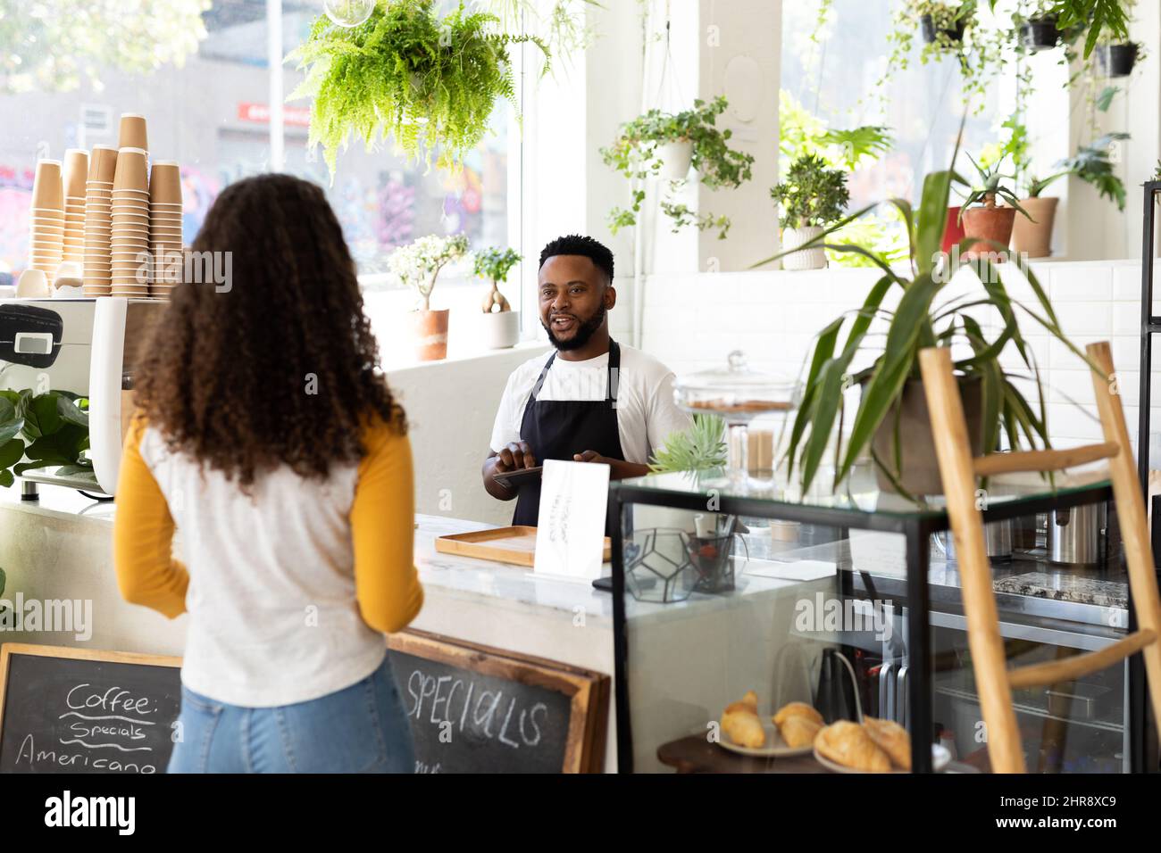 Barista e cliente afro-americano che parla al banco del caffè Foto Stock