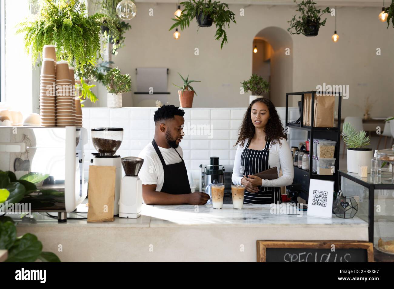 Giovani baristi afroamericani maschi e femmine in piedi con caffè ghiacciato al banco del bar Foto Stock