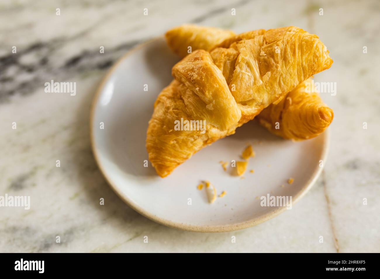 Primo piano ad angolo di cornetti freschi serviti in un piatto di marmo presso la caffetteria Foto Stock