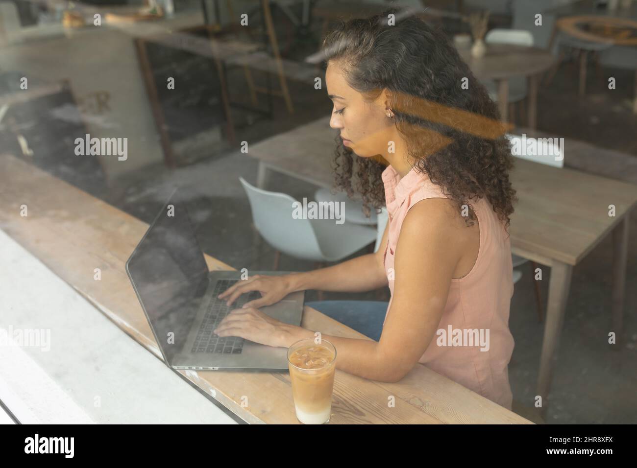 Cliente afro-americano che utilizza un computer portatile visto attraverso la finestra del bar Foto Stock