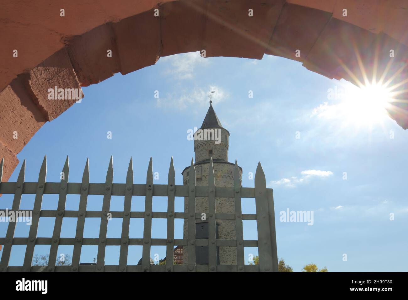 Vista della torre delle streghe, retroilluminata attraverso il cancello, giardino del castello a Idstein im Taunus, Hesse, Germania Foto Stock