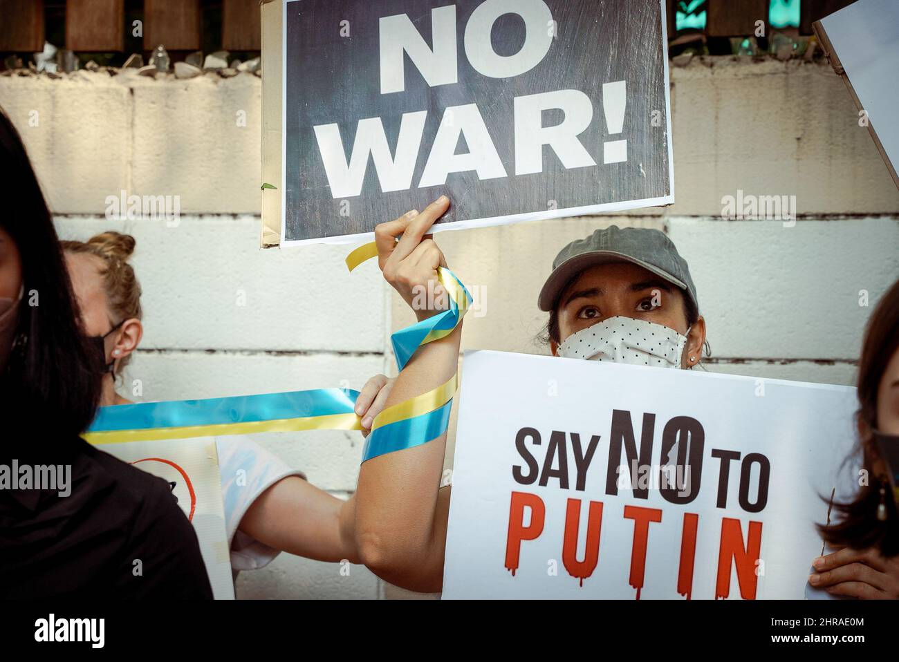 Bangkok, Tailandia. 25th Feb 2022. Una donna in un cappello da baseball tiene due cartelli che dicono 'No War' e 'Say no to Putin', durante la manifestazione. I manifestanti si sono riuniti fuori dall'Ambasciata russa a Bangkok per denunciare l'invasione russa sull'Ucraina. Oltre cinquanta si trovavano fuori dalle porte dell'ambasciata, cantando l'inno nazionale ucraino e tenendo segnali che richiedevano sanzioni e embarghi di petrolio e gas. (Foto di Mailee Osten-Tan/SOPA Images/Sipa USA) Credit: Sipa USA/Alamy Live News Foto Stock