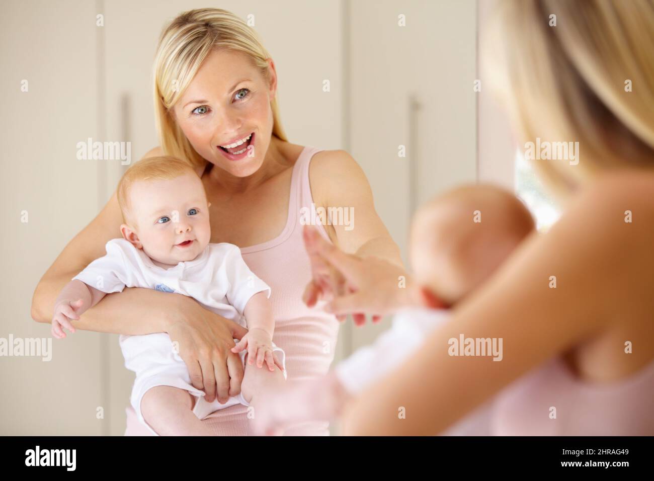 Quella ragazza piccola carina è voi.... Una ragazza carina del bambino che guarda se stessa nello specchio mentre la sua mamma punta. Foto Stock