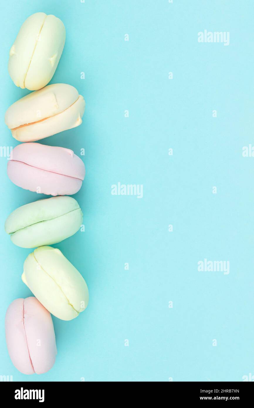 Primo piano di marshmallow assomiglia a torte di amaretti di colori diversi su sfondo blu Foto Stock