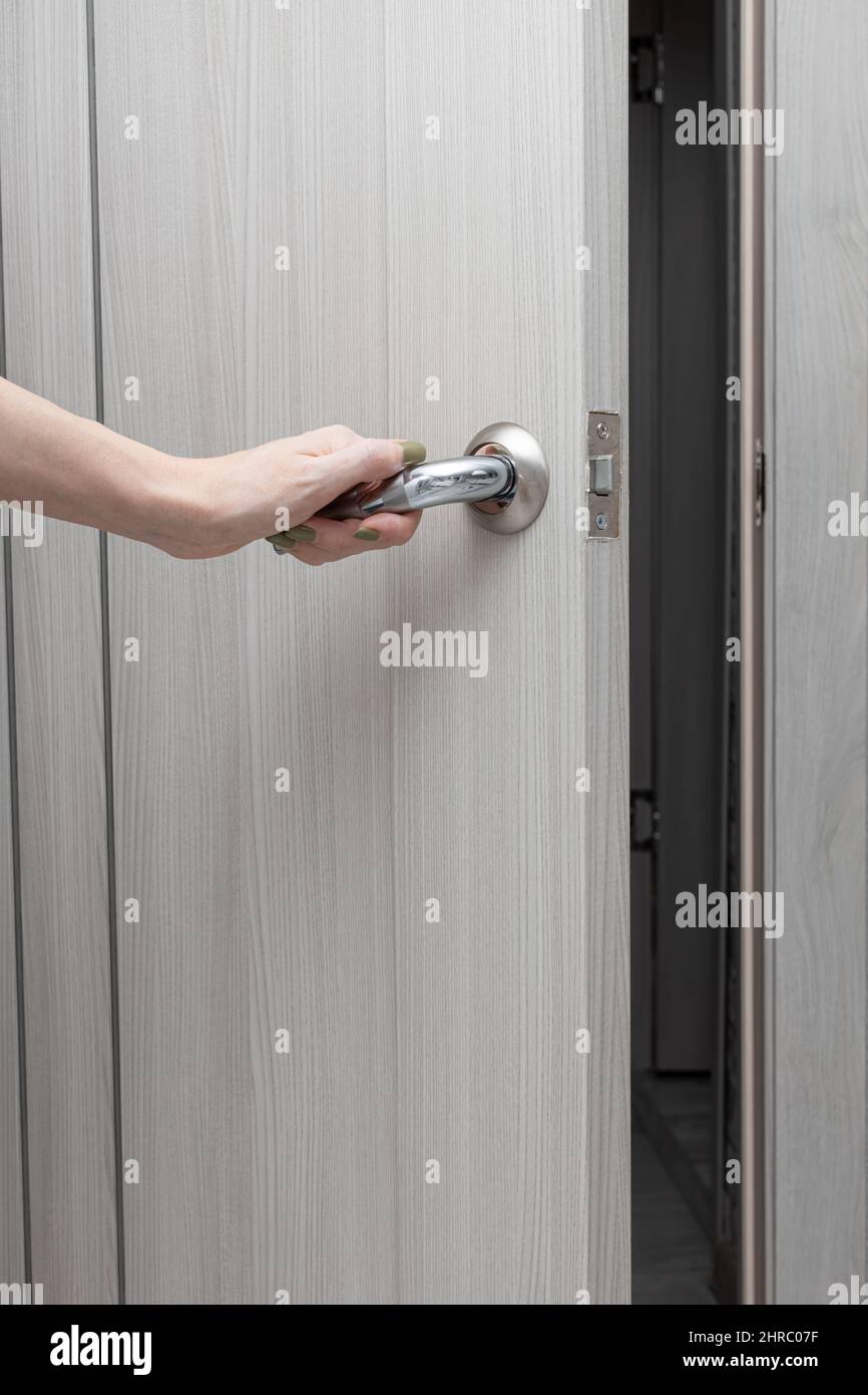 la mano di una donna apre una porta interna accanto alla maniglia. Foto di alta qualità Foto Stock