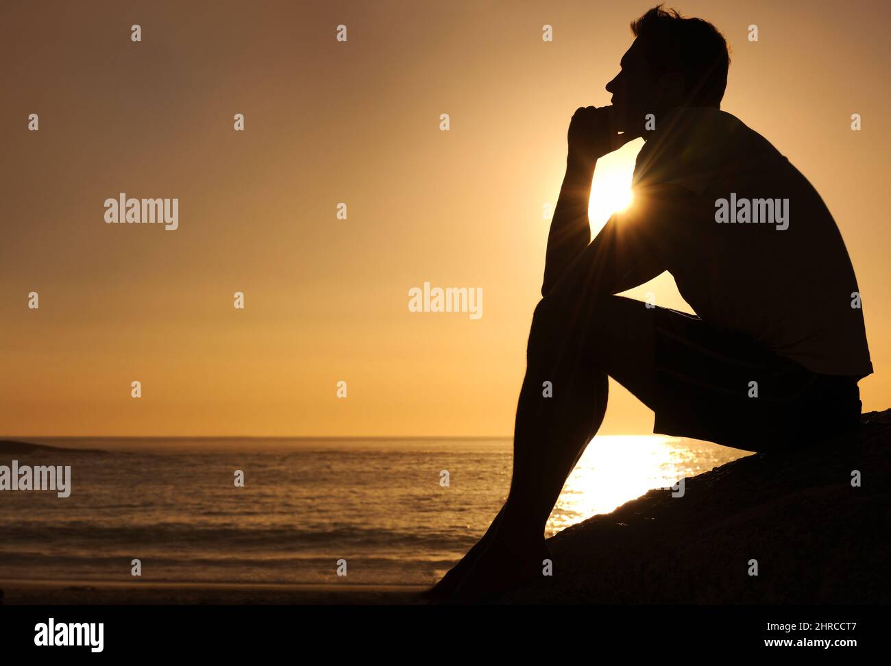 Ricerca di risposte lifes. Silhouette di un uomo pensieroso seduto accanto all'oceano - copyspace. Foto Stock