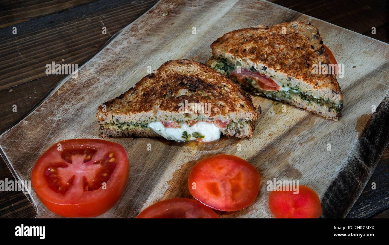 Panino tostato con mozzarella e pomodori sul tagliere Foto Stock