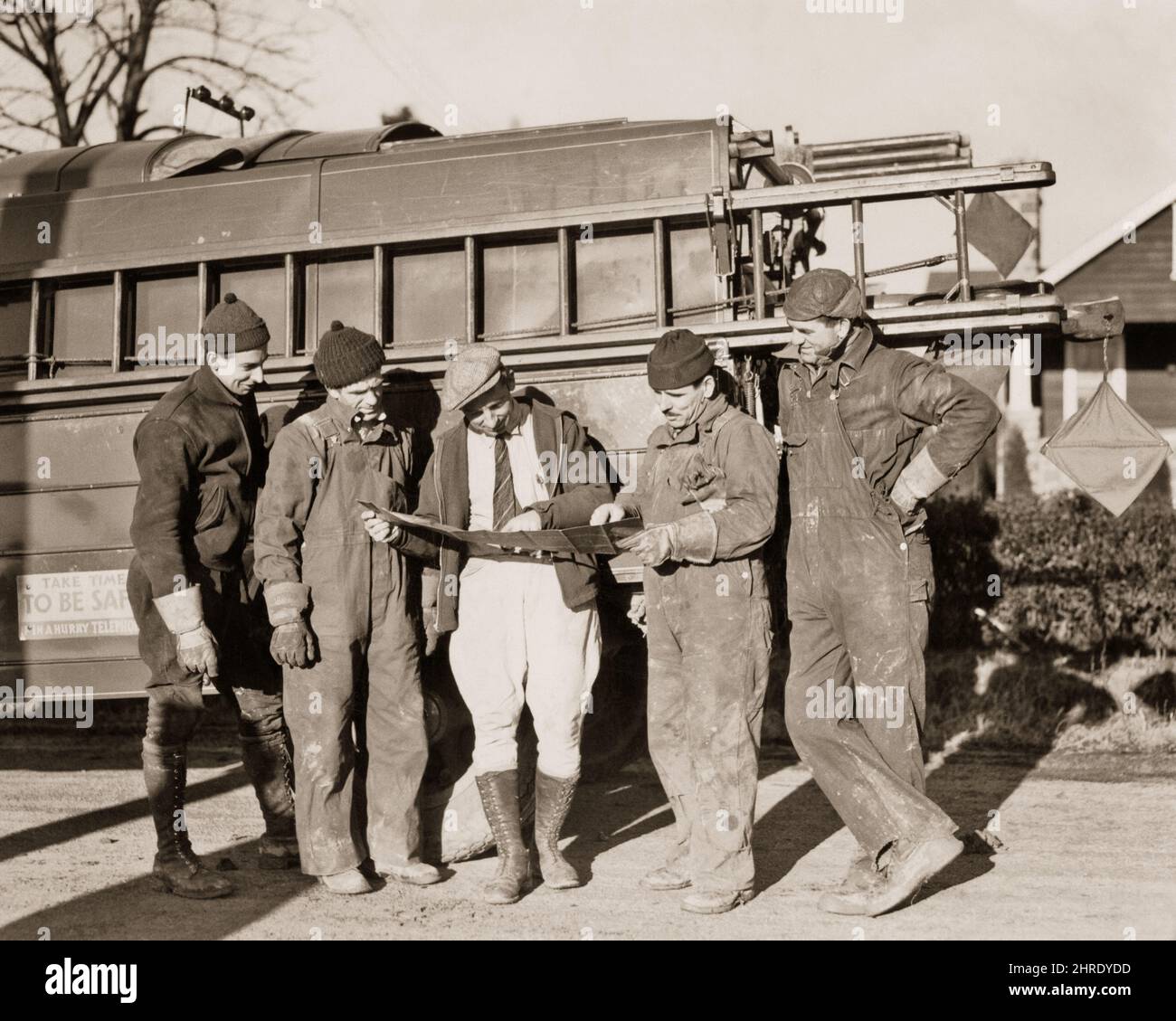 1930S SUPERVISORE IN BERRETTO PIATTO E JODHPURS CON QUATTRO UOMINI EQUIPAGGIO DI COSTRUZIONE ACCANTO A CAMION CON SCALE E ATTREZZATURE GUARDARE A MAP - I3297 HAR001 HARS TRASPORTO B&W ABILITÀ DI OCCUPAZIONE E LAVORO DI LAVORO DI LAVORO A IN SCALE DI LAVORO DI SUPERVISORE OCCUPAZIONI AL DI LÀ DELLE INFRASTRUTTURE DIPENDENTI JODHPURS LINEMEN MEDIO-ADULTO UOMO MEDIO-ADULTO GIOVANE ADULTO UOMO NERO E BIANCO ETNIA CAUCASICA HAR001 LAVORO VECCHIO ALLA MODA Foto Stock