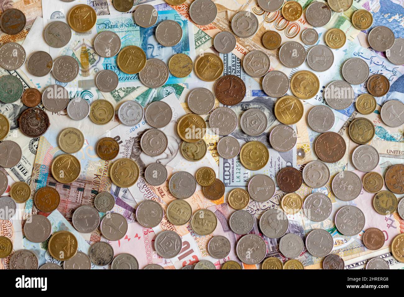 Monete diverse su banconote in valute mondiali Foto Stock