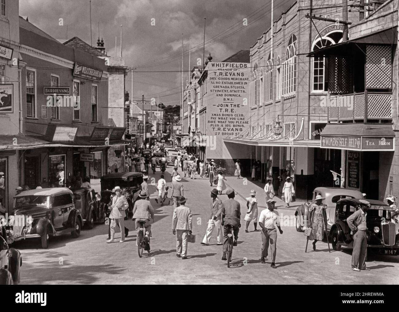 1930S 1940S AFFOLLATO BORDO STRADA PEDONI NEGOZI DI AUTOMOBILI A BRIDGETOWN BARBADOS IN PICCOLE ANTILLE DELLE INDIE OCCIDENTALI - R12559 PAL001 HARS LADIES PERSONE NEGOZI AUTO MASCHI EDIFICI PEDONI BICICLETTE TRASPORTO B&W BICICLETTE SHOPPER ACQUIRENTI INDIES ALTA ANGOLO PROPRIETÀ AUTOS NEGOZI ESTERNI PICCOLE STRUTTURE IMMOBILIARI AUTOMOBILI VEICOLI EDIFICE ANTILLE BARBADOS ISLAND PAESE COMMERCIO COOPERAZIONE NERO E BIANCO IMPRESE CAUCASICHE ETNIA VECCHIO STILE Foto Stock