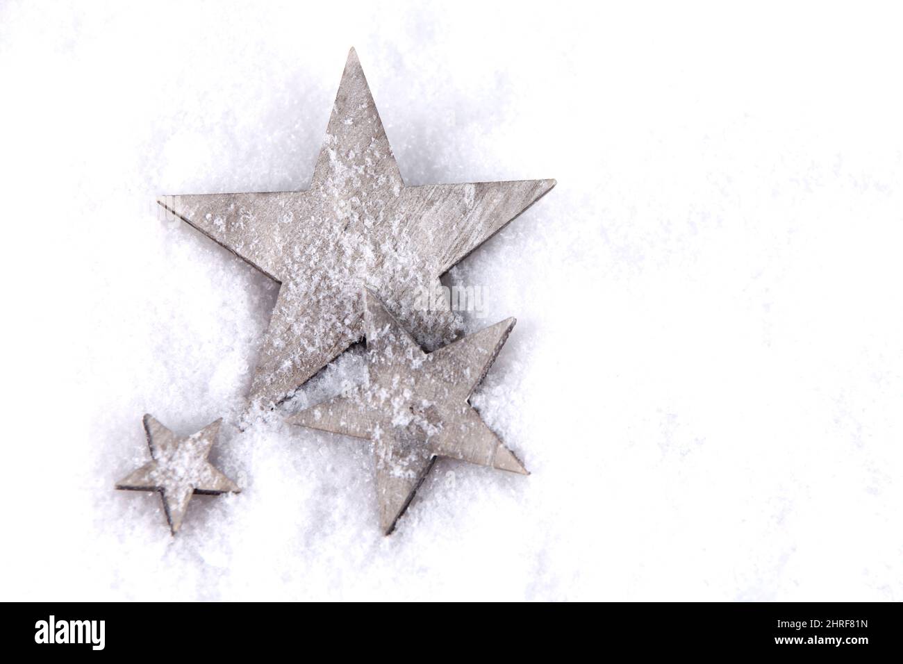 Una vista dall'alto di stelle decorative in legno su uno sfondo bianco nevoso con un copyspace Foto Stock