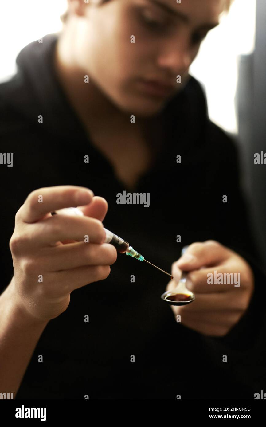 Lungo un percorso scuro. Colpo di un giovane che prepara un colpo di eroina. Foto Stock