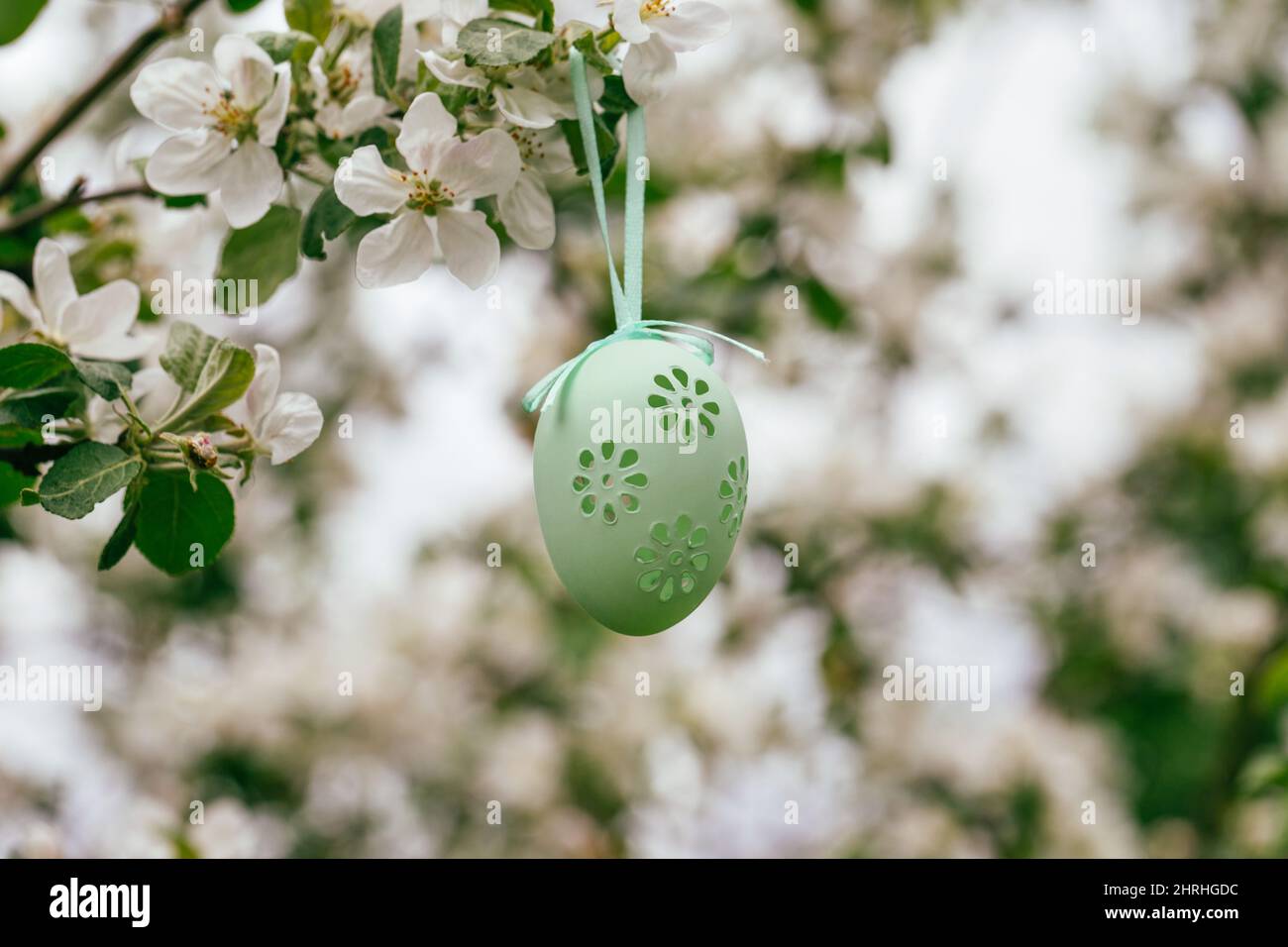 Uovo decorativo pasquale appeso su un melo fiorente. Periodo di Pasqua. Arredamento festivo. Foto Stock