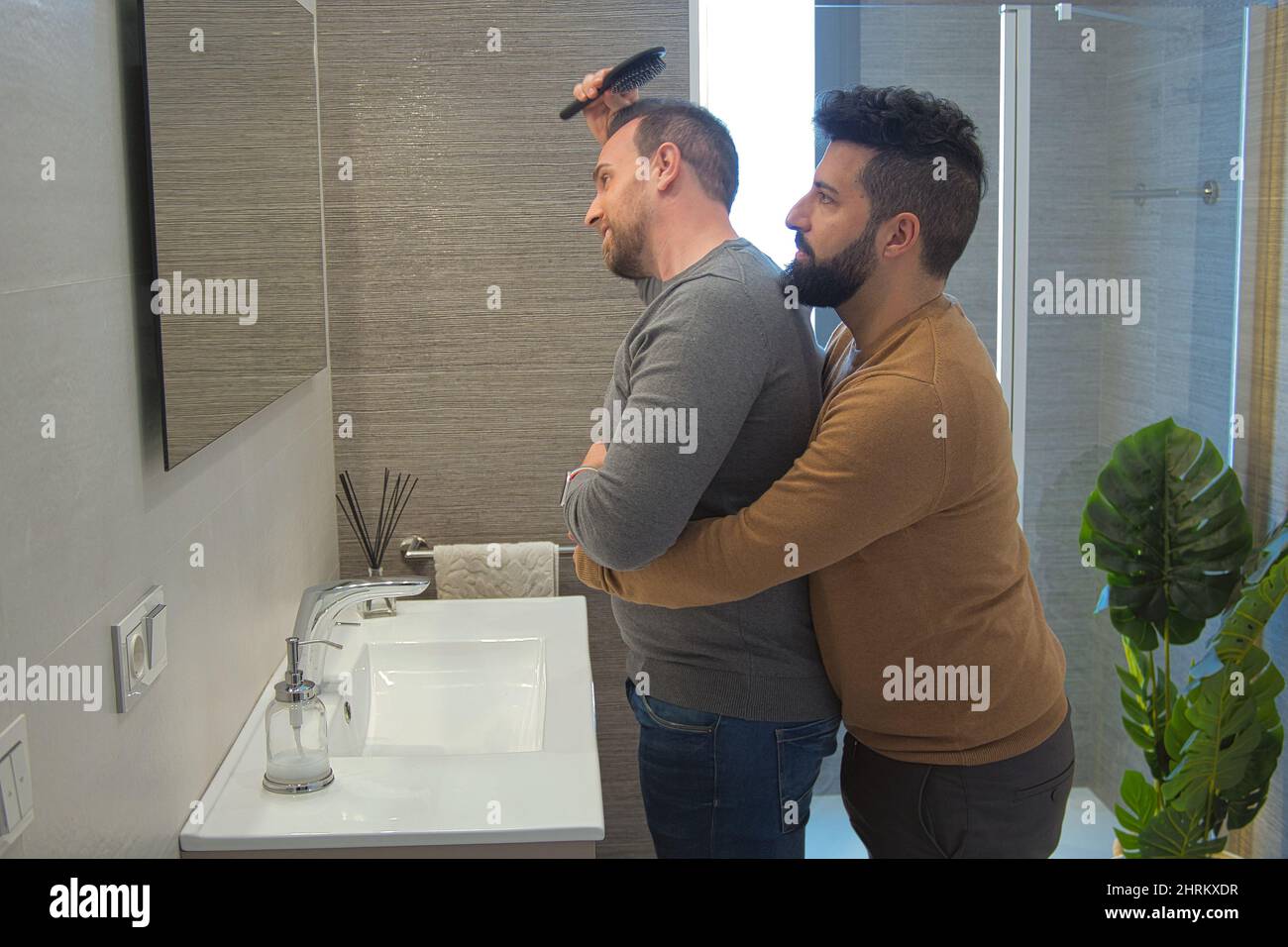 Primo piano di un gay sposato abbracciando nel bagno della loro casa Foto Stock