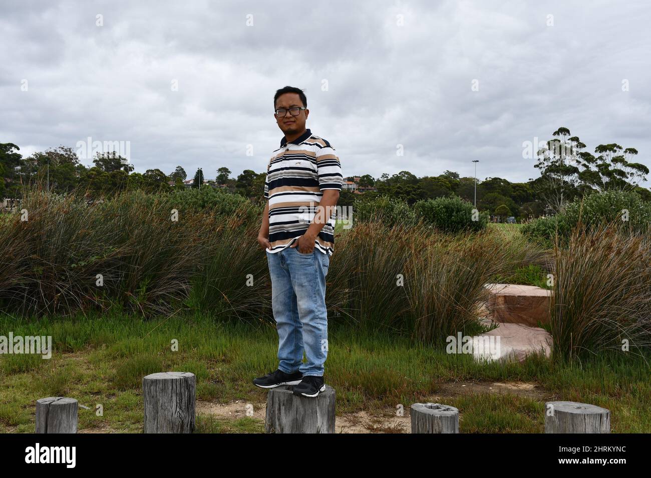Giovane uomo in piedi sui ceppi nel parco. Foto Stock