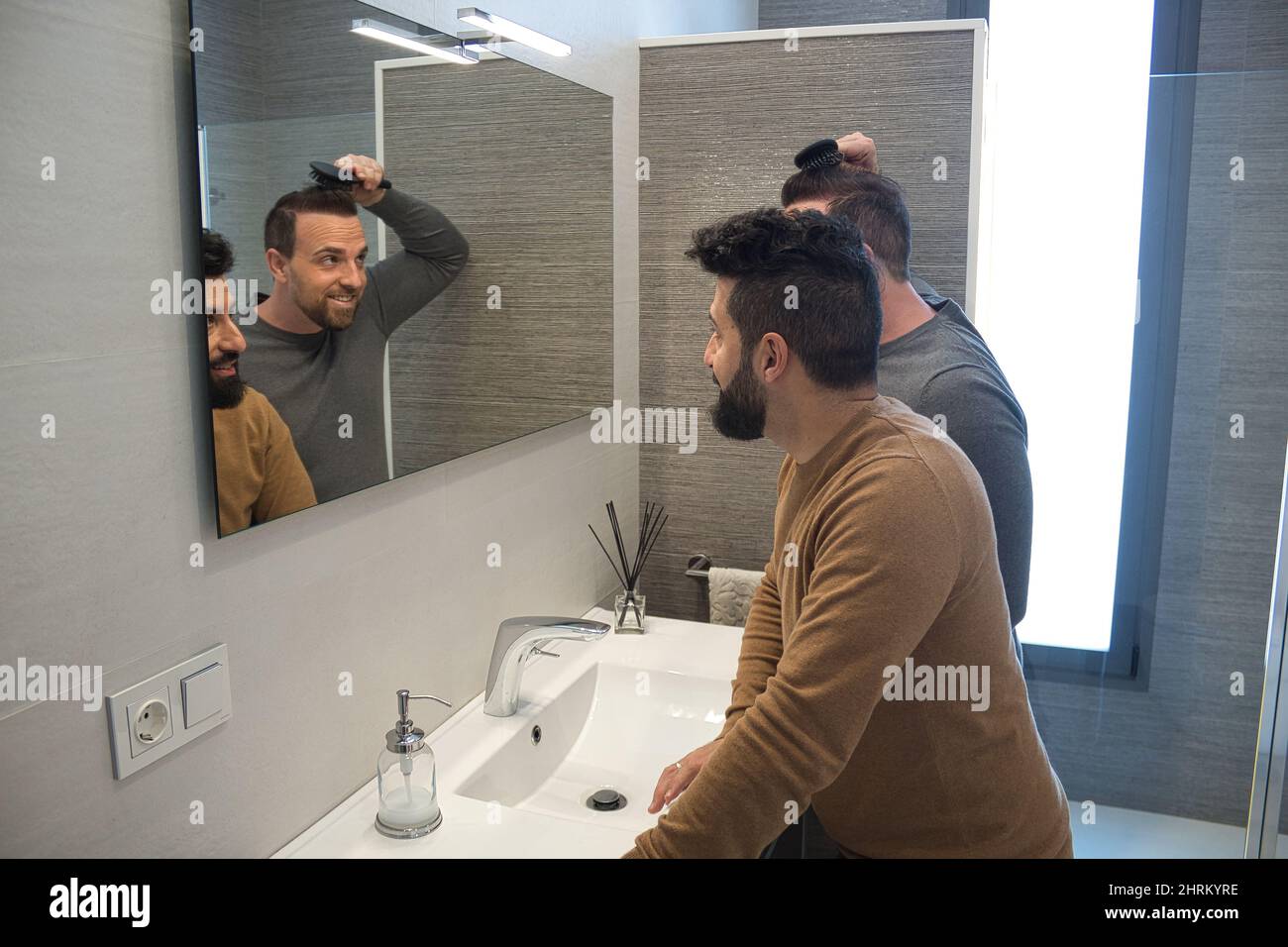 Primo piano di un gay sposato abbracciando nel bagno della loro casa Foto Stock
