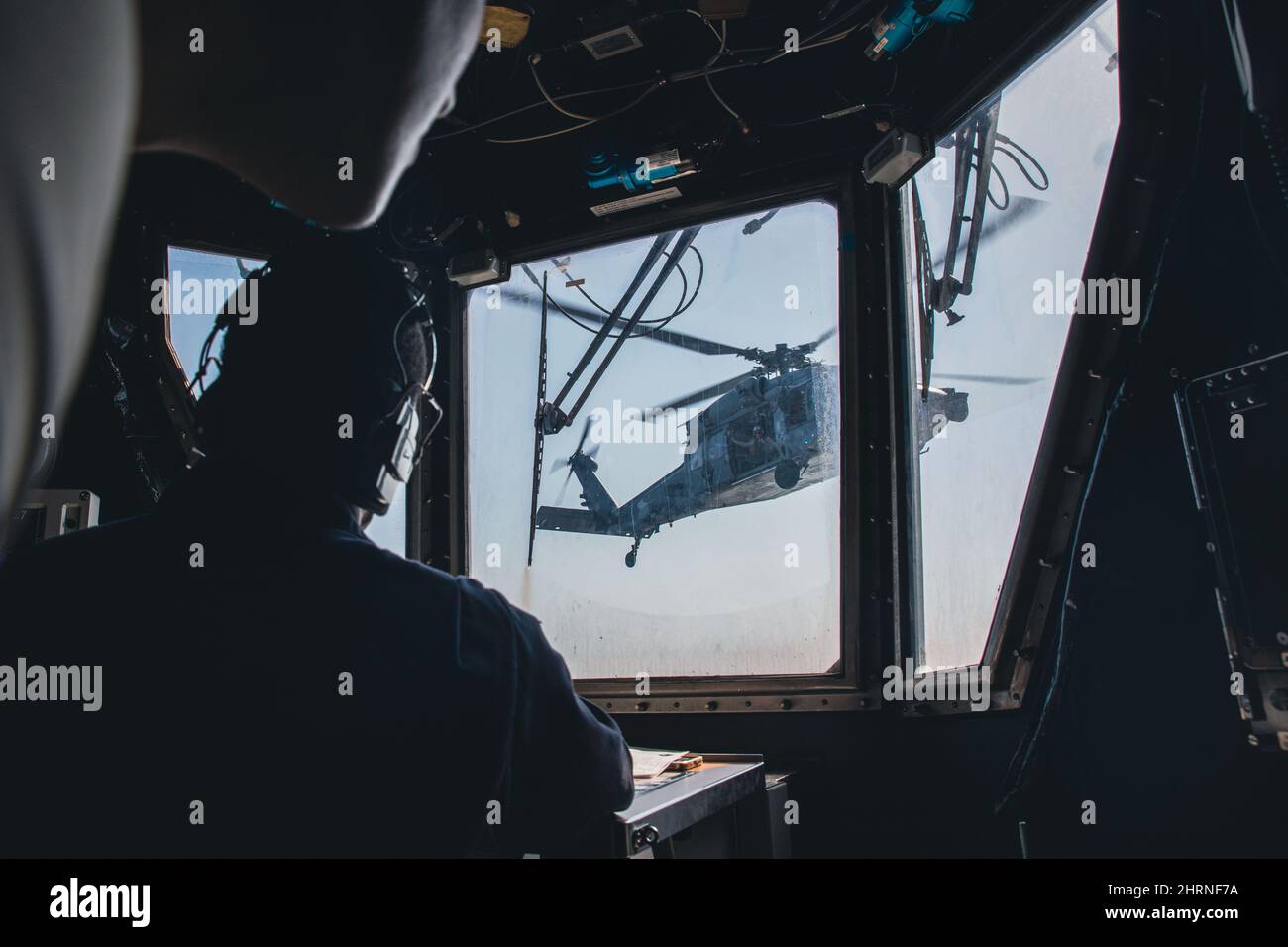 220222-N-GF955-1005 MAR DEI CARAIBI - (DAL 21, 2022) -- Boatswain's Mate 1st Classe Emmanuel Dixon assegnato alla nave da combattimento litoranea in libertà USS Billings (LCS 15) osserva dalla torre di controllo del volo come elicottero MH-60s Sea Hawk, assegnato alla “Shadow Det” della Helicopter Sea Combat Squadron (HSC) 28, distaccamento 7, Decollo dal ponte aereo, 21 febbraio 2022. Billings è dispiegato nell'area delle operazioni della flotta USA 4th per sostenere la missione della Joint Interagency Task Force South, che include missioni di lotta contro il traffico illecito di droga nei Caraibi e nell'Est del Pacifico. (STATI UNITI Foto Stock