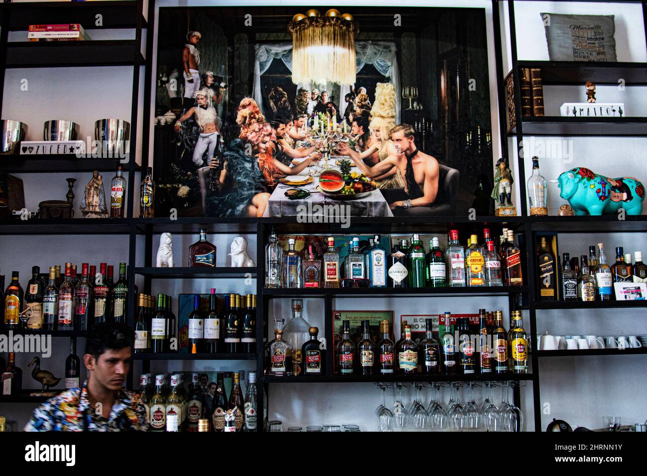 All'interno di un elegante ristorante e bar cubano dove il barman sta facendo bevande con bevande alcoliche in mostra e belle opere d'arte murali cubane. Foto Stock