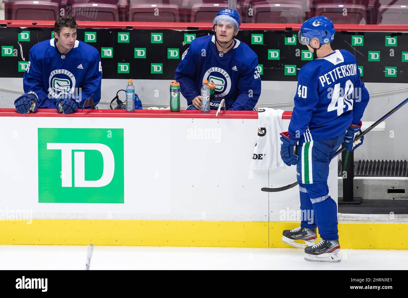 Vancouver Canucks' Quinn Hughes, a sinistra, e Bo Horvat, al centro, si siedono sulla panchina mentre Elias Pettersson, di Svezia, si skates sopra per parlare dopo back-to-back su sessioni di ghiaccio durante il campo di addestramento della squadra di hockey NHL, a Vancouver, lunedì 13 luglio 2020. LA STAMPA CANADESE/Darryl Dyck Foto Stock