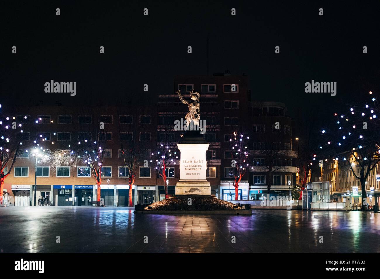Statua di Jean Bart circondata da alberi illuminati ed edifici a Dunkirk, Francia Foto Stock