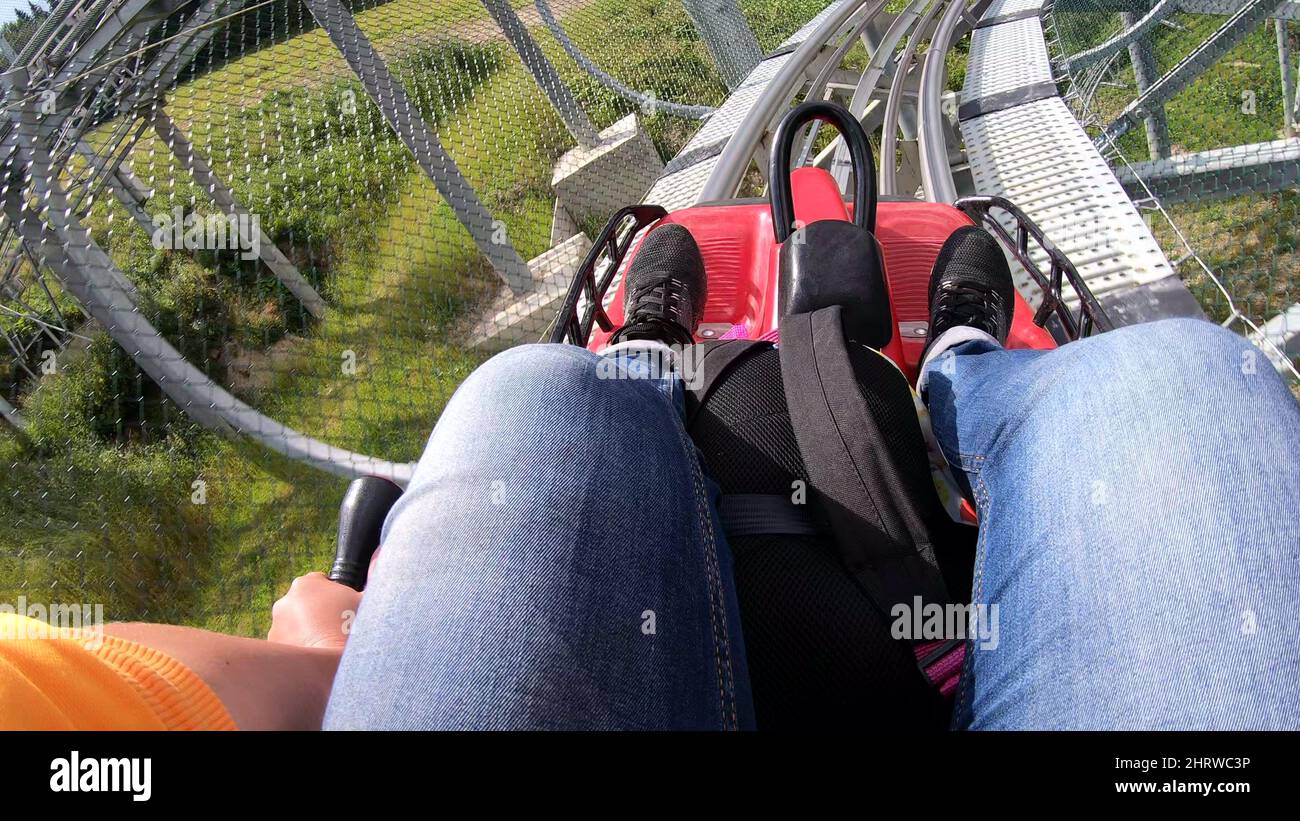 La persona corre in veloce rodelbahn slittino in montagna in boschi tra gli alberi Foto Stock