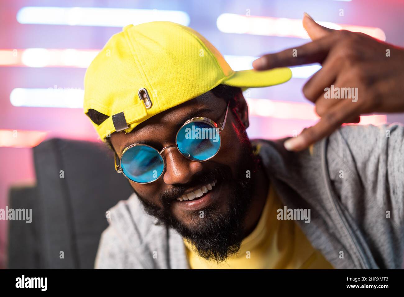 primo piano del canto del rapper hip hop guardando la macchina fotografica su sfondo neaon - concetto di musica hip hop, cantante professionista e intrattenimento Foto Stock