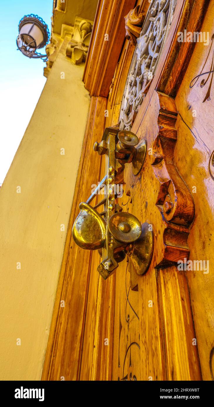 Foto verticale di una parte di una porta in legno d'epoca e di un bussatore dorato Foto Stock