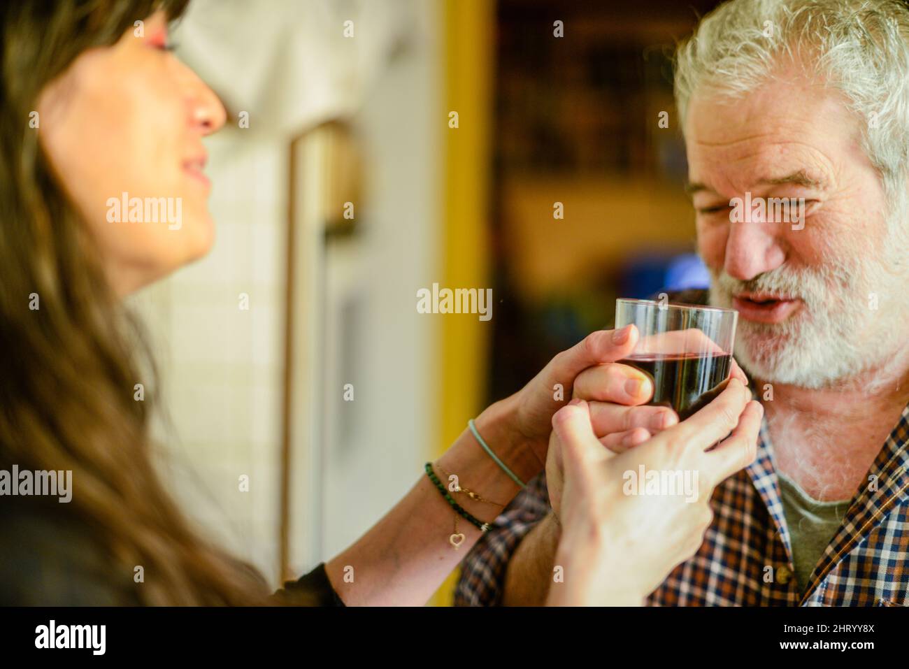 l'uomo anziano caucasico beve vino e bevendo a casa sottolineando la giovane moglie ispanica - alcolismo e violenza domestica concetto Foto Stock