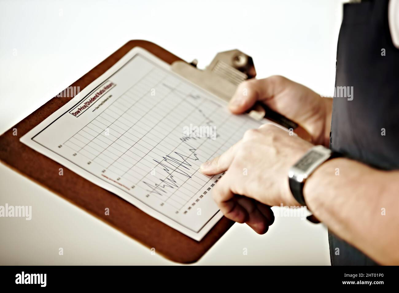 Monitoraggio del mercato a lungo termine. Una persona che punta a un grafico in una clipboard. Foto Stock