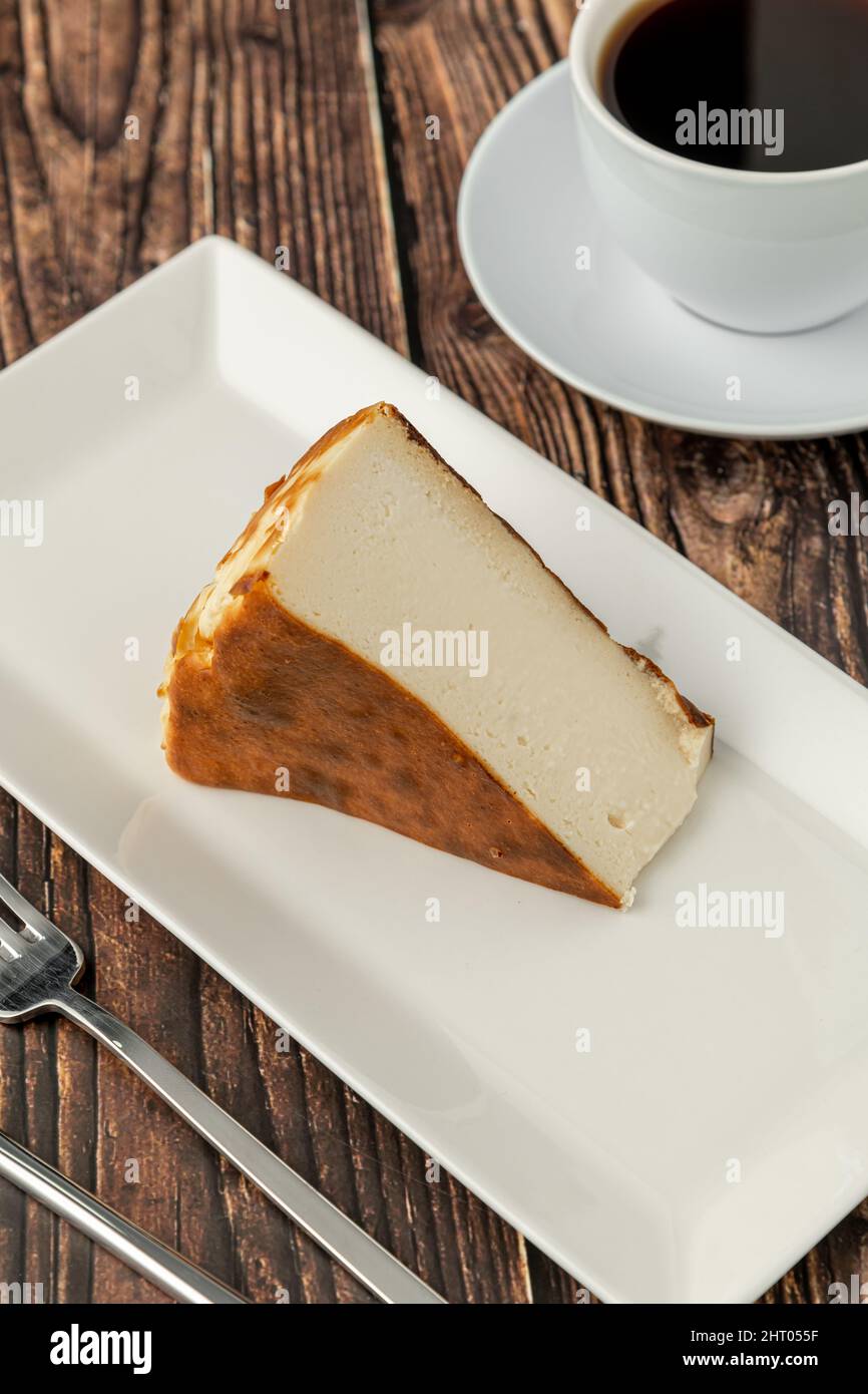 Cheesecake a fette di san sebastian con caffè su tavola di legno Foto Stock